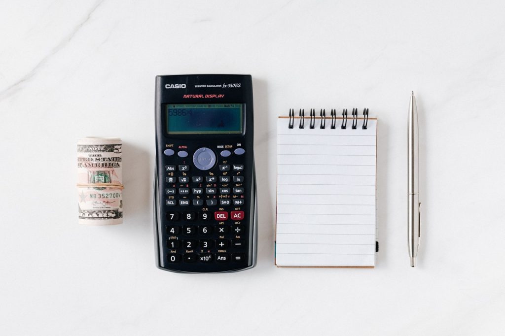 Image of calculator, notepad, and roll of cash donations for nonprofit annual report.