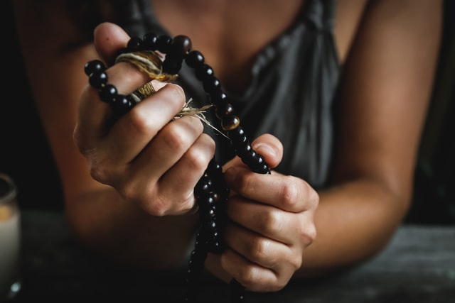 A woman holds religious prayer beads.