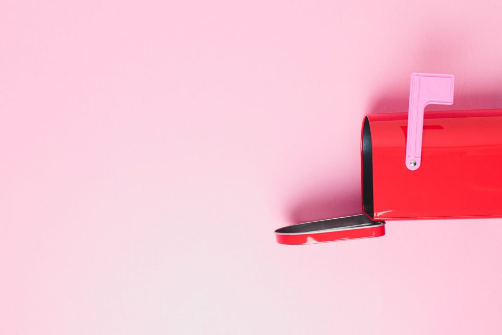 Open red mailbox with pink wall