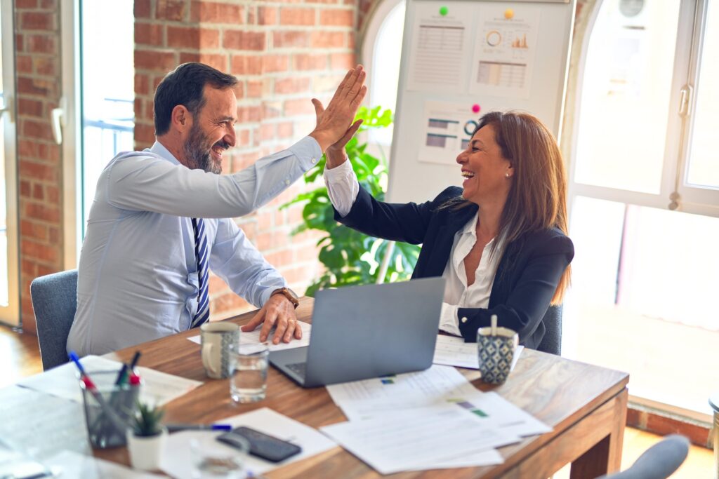 Man and woman high five each other across work table